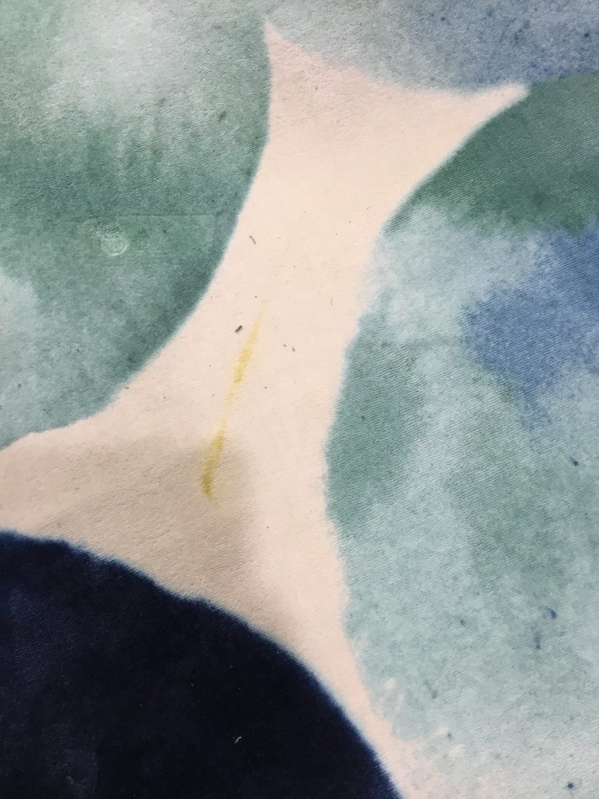 Yellow streak stain on the ivory field of a wool rug