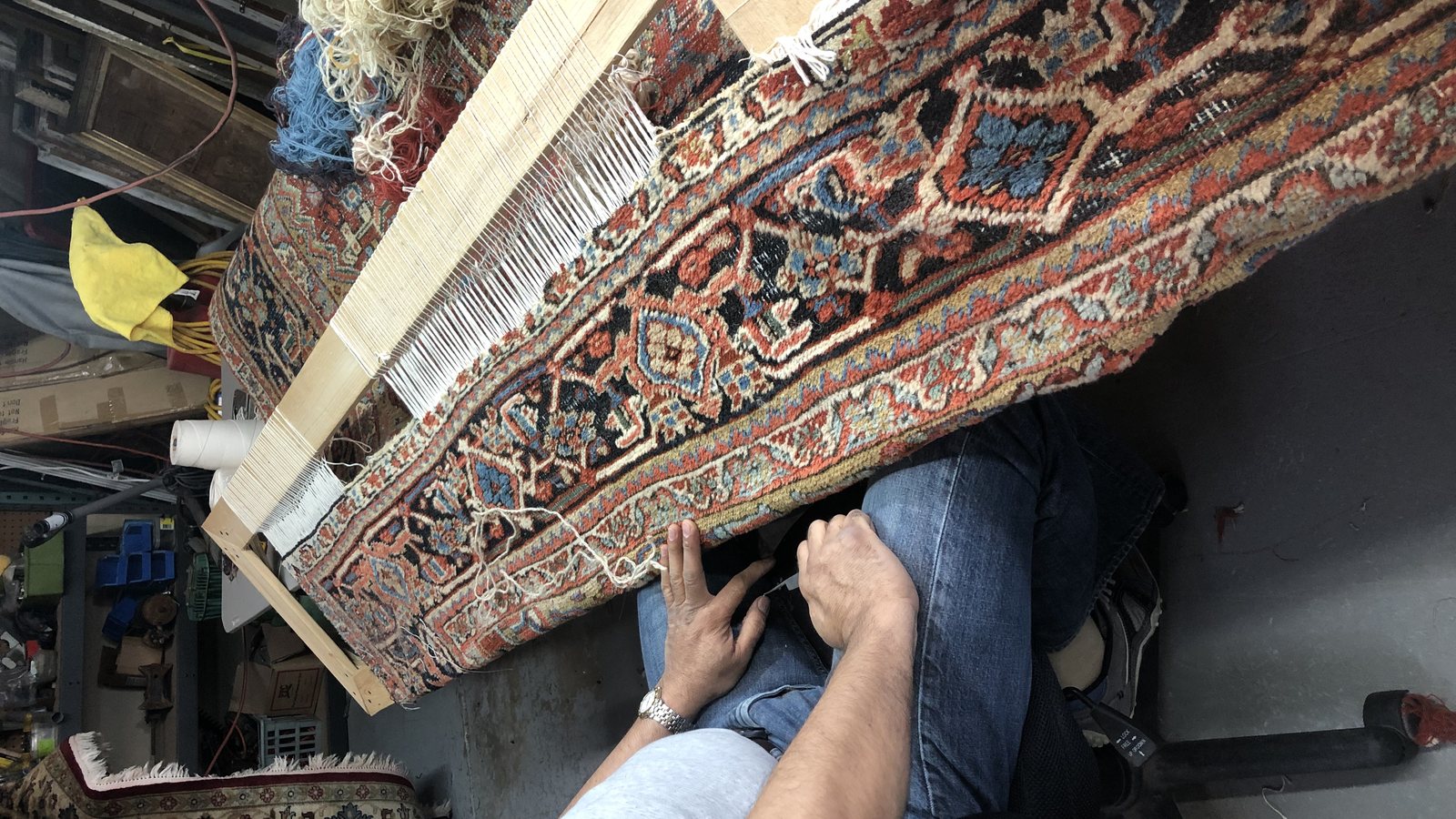 Hands reworking a rug fringe back into the foundation