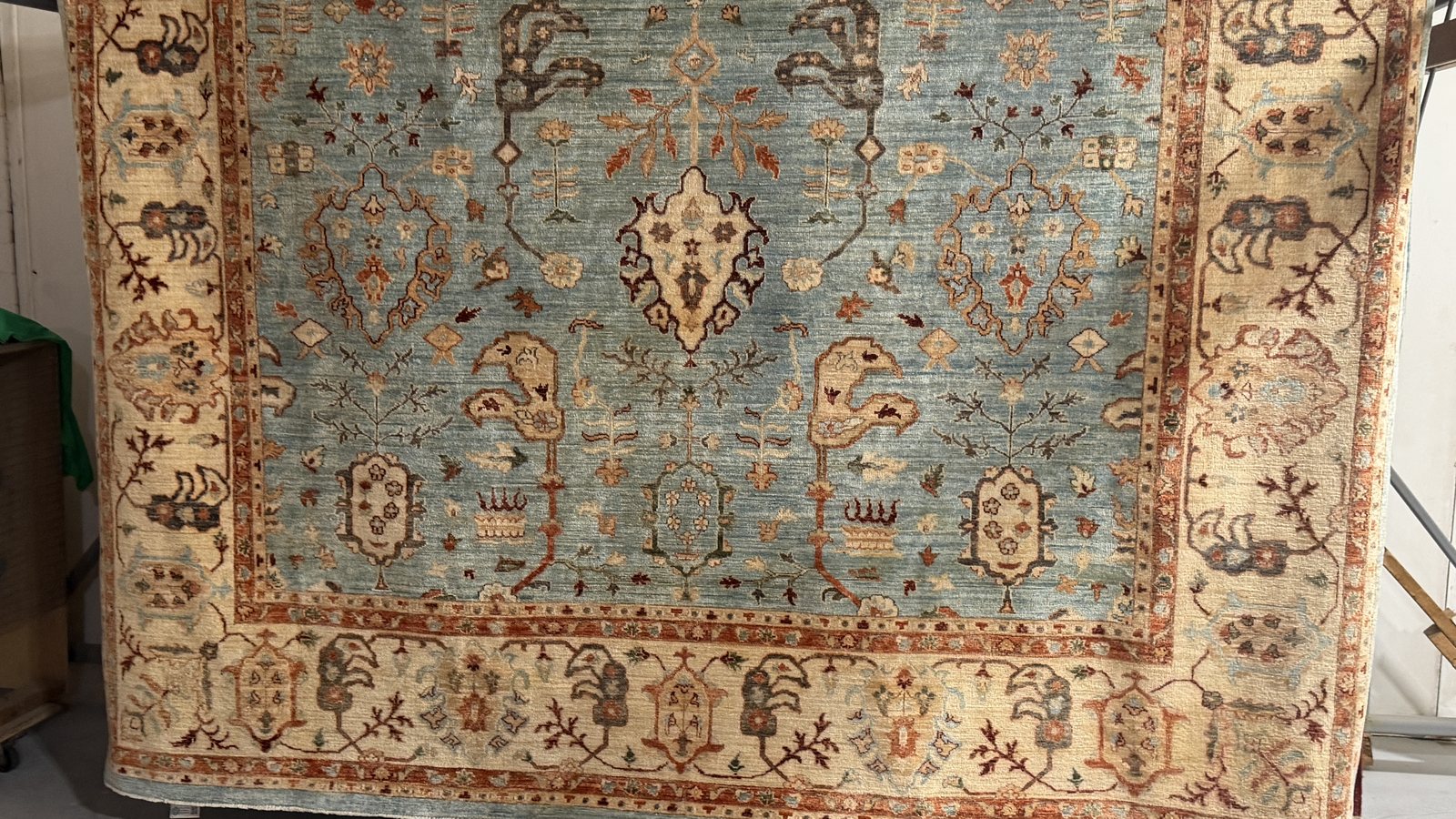 A washed rug hanging to dry on the rack, light showing through the weave