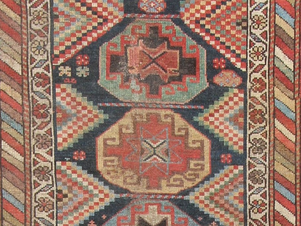 Caucasian rug detail with bold angular medallions and high-contrast colour